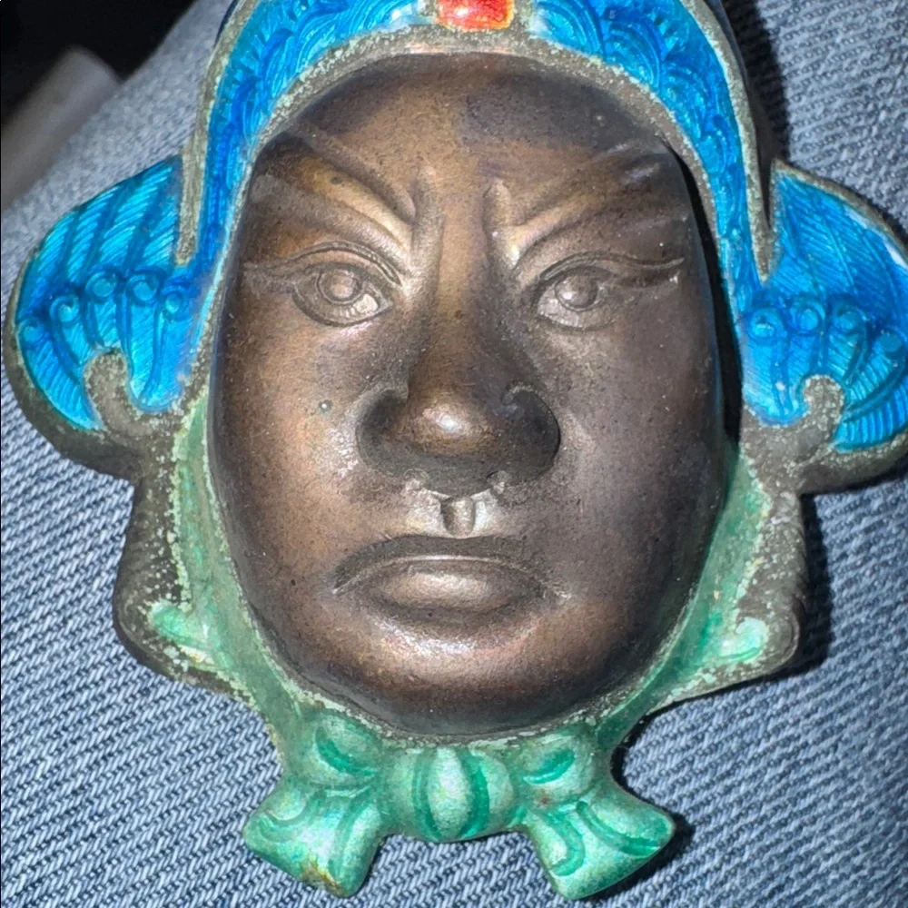 Vintage enameled metal decorative mask of an Asian man's face.